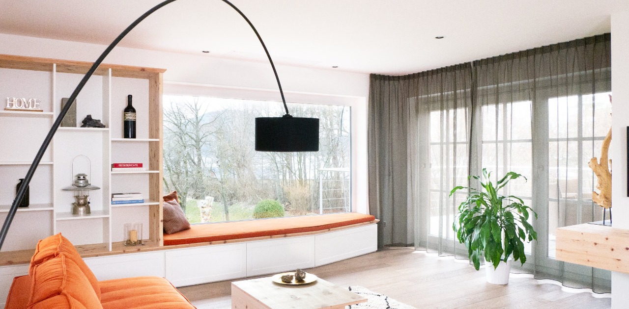 Wohnzimmer mit Liegebank am Fenster und integriertem Bücherregal