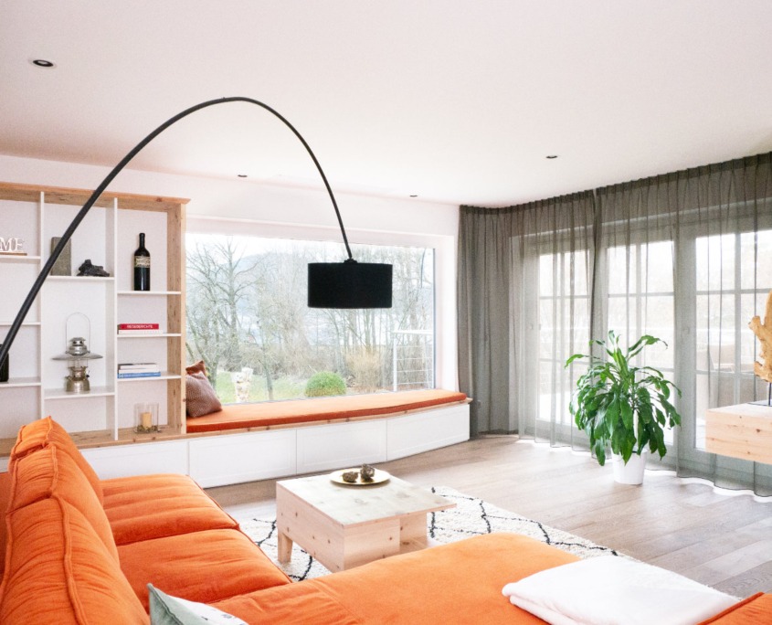 Wohnzimmer mit Liegebank am Fenster und integriertem Bücherregal