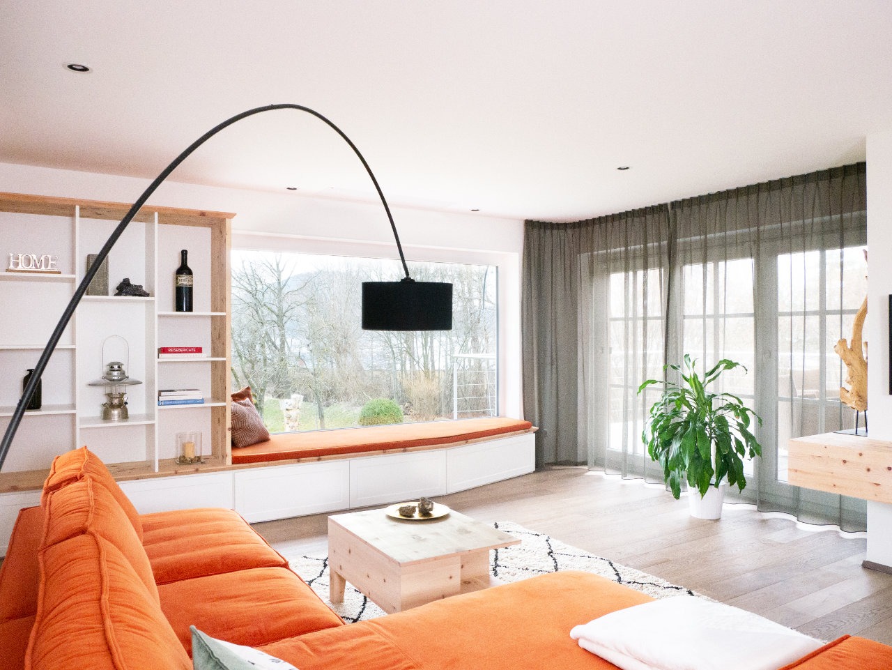 Wohnzimmer mit Liegebank am Fenster und integriertem Bücherregal