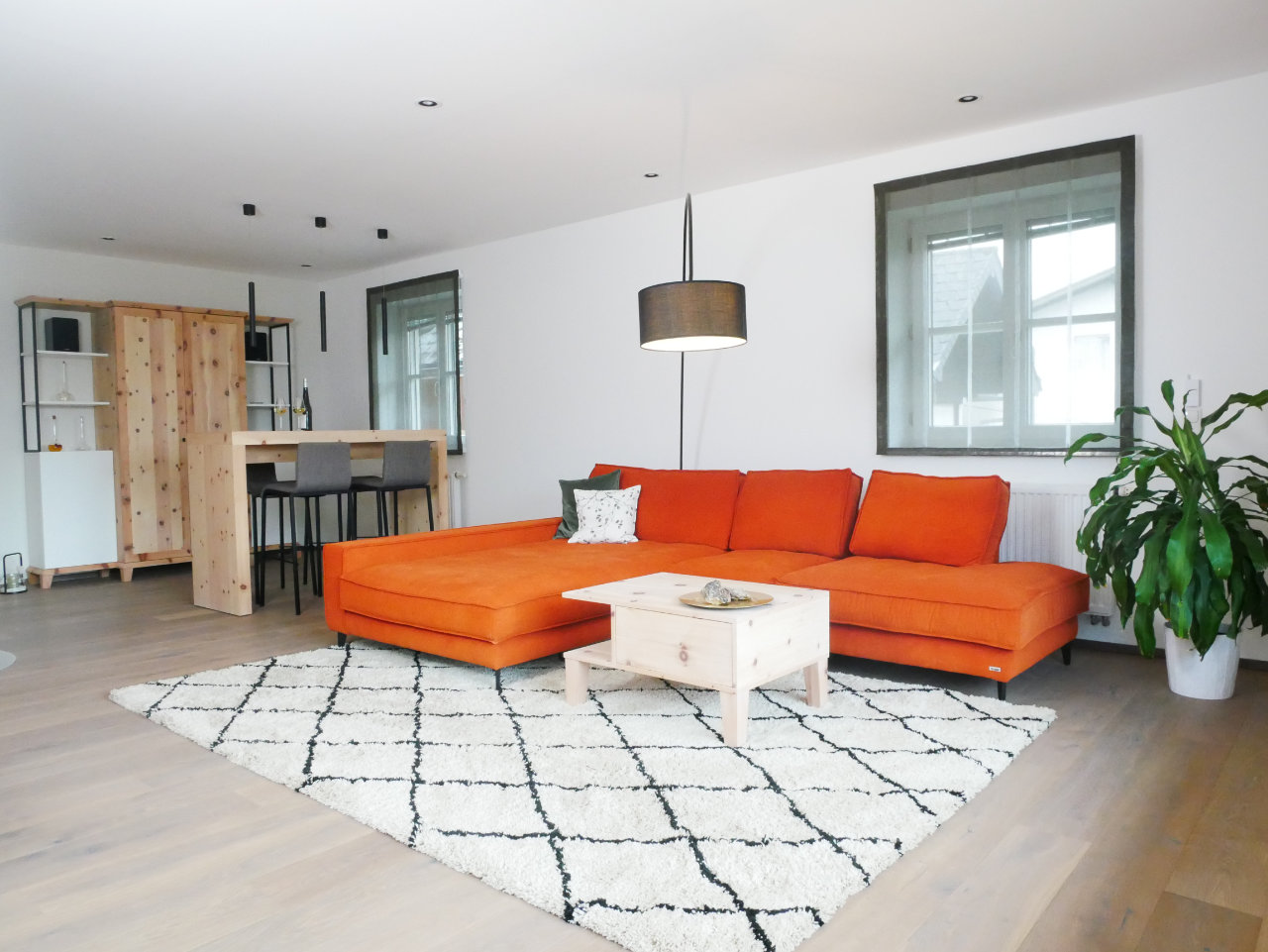 Wohnzimmer mit Zirbenholzmöbel und oranger Couch