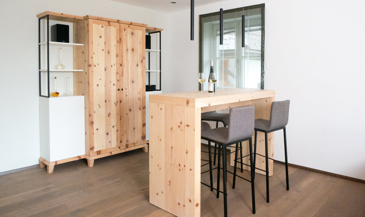 Barschrank und Stehtisch aus Zirbenholz im Wohnzimmer, schwarze Hängeleuchten