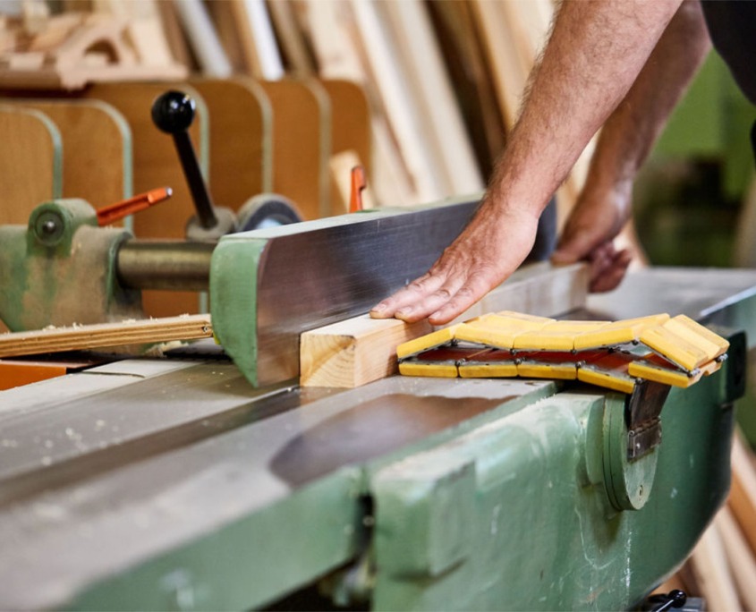 Tischlerhände an der Abrichthobelmaschine